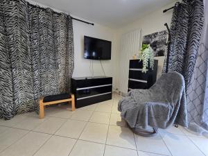 a living room with a chair and a television at STUDIO Confort Clim 20min Orly-45min Paris Disney in Corbeil-Essonnes