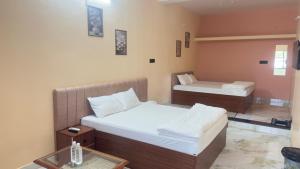 a hotel room with two beds and a table at Hotel Prisha Recidency in Wardha