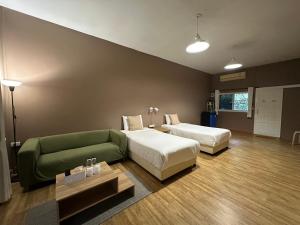 a hotel room with two beds and a green couch at Khao Yai Cottage in Mu Si