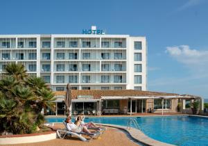 a hotel with people sitting in chairs by the pool at RVHotels Nieves Mar in L'Escala