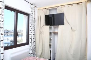 a living room with a tv and a window at Beautiful cocoon with shared pool in Le Barcarès in Le Barcarès