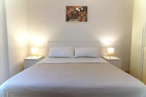 a bedroom with a white bed with two lamps at Appartamento con veranda tra Roma e il mare in Vitinia