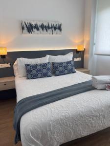 a bedroom with a large bed with blue and white pillows at Alojamientos Dima Costa in Laredo