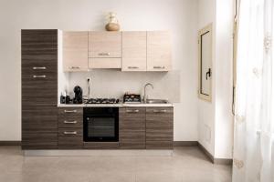 a kitchen with wooden cabinets and a stove top oven at Maison Alexeur - Intero Appartamento in Crotone