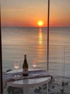 a bottle of wine and two glasses on a table with the sunset at RVHotels Nieves Mar in L'Escala