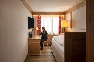 a woman sitting at a desk in a hotel room at The Glacier Hotel - ex Eurotel Victoria - in Les Diablerets