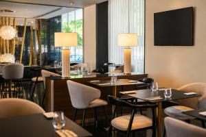 een restaurant met tafels, stoelen en lampen bij BessaHotel Boavista in Porto