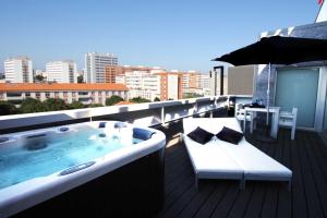 een jacuzzi op een balkon met een parasol bij BessaHotel Boavista in Porto