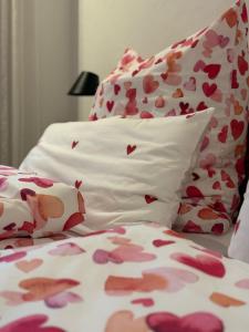 a bed with pink and white sheets and pillows with hearts at Chalet22 beim Flößerhaus in Beuerberg in Eurasburg +17 photos
