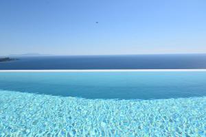 a pool of water with the ocean in the background at Apiron Luxury Villa in Agía Kyriakí
