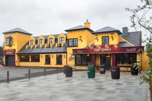 ein großes gelbes Gebäude mit einem davorliegenden Parkplatz in der Unterkunft Tigh Mary Donals Bar & Rooms at Whitegates in Killarney
