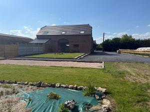 a house with a pond in the yard at Le domaine de l'Ebenne in Englefontaine