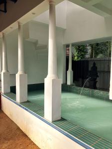 a swimming pool with four columns and a fountain at Aali villas in Mararikulam