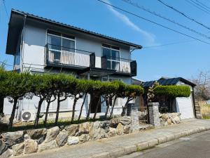 a house with a stone retaining wall and trees at Biwa Asahi 家族友人大人数ok BBQok in Takashima