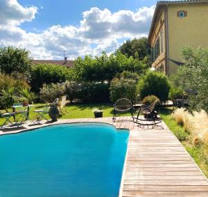 a swimming pool with chairs and a wooden deck at 3 chambres d'hôtes de charme avec jacuzzi & sauna au Clos de la Lèze in Lézat-sur-Lèze