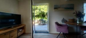 a living room with a television and a table and a patio at De Strandloper in Petten