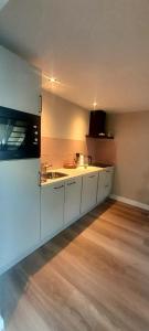 a kitchen with white cabinets and a wooden floor at De Strandloper in Petten