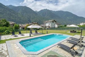 a swimming pool with chairs and a house and mountains at Spinedi Royale in Postalesio