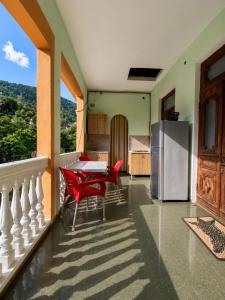 a kitchen with a table and red chairs on a balcony at Guesthouse Tornike in Gonio