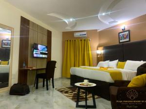 a hotel room with a bed and a table and a tv at Pearl Paradise Resort by 4E in Finima