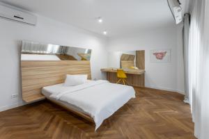 a bedroom with a white bed and a wooden floor at Aparthotel Blend City Center in Bucharest