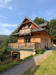 a log house with a balcony and a porch at Uroczysko in Brenna