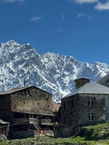 a building with a snow covered mountain in the background at Poli in Ushguli