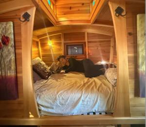 Eine Frau liegt auf einem Bett in einem Holzzimmer. in der Unterkunft Bitty Bunky in Nelson