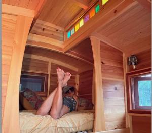 eine Person, die auf einem Bett in einem Baumhaus liegt in der Unterkunft Bitty Bunky in Nelson