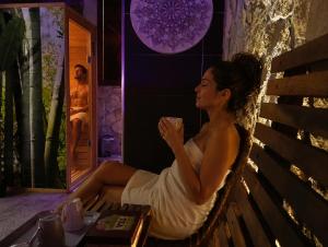 a woman sitting on a bench drinking a drink at SPA ROOM SICILIA - Suite con Spa ad uso esclusivo Jacuzzi Sauna Hammam in Rosolini