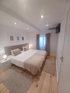 a bedroom with a large white bed and wooden floors at Flor do Padrão in Elvas
