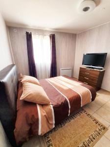 a bedroom with a bed and a flat screen tv at Maison confortable à Ver-sur-Mer avec jardin privé in Ver-sur-Mer