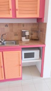 a pink kitchen with a microwave and a sink at Appartement charmant à Baie Mahault avec belle terrasse – 30 m² in Baie-Mahault +17 photos