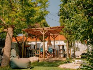 a wooden pavilion with a table and chairs in a yard at Hospedium República Surf House - Coxos Beach, Ericeira in Ericeira