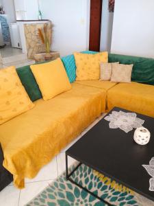 a couch with mustard colored cushions in a living room at Appartement confortable à Sainte-Luce avec jacuzzi in Sainte-Luce
