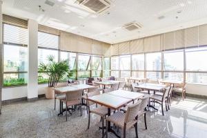 a dining room with tables and chairs and windows at Living Sion in Belo Horizonte