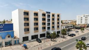 a white building on a city street with cars at AB Business Hôtel in Nouakchott