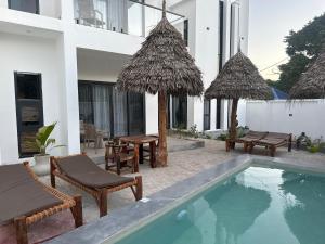 a pool with chairs and umbrellas next to a building at Lala salama Kendwa villas in Kendwa