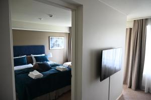 a bedroom with a blue bed and a television at Boutique hotel SAVOIR in Savonlinna