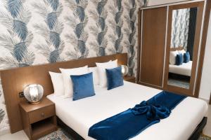 a bedroom with a bed with blue pillows and a mirror at AB Business Hôtel in Nouakchott