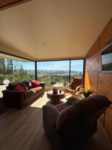a living room with two couches and a large window at Cabañas Vista Volcanes del Sur in Llanquihue