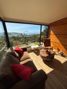 a living room with a couch and a large window at Cabañas Vista Volcanes del Sur in Llanquihue