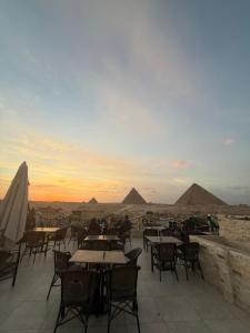 a patio with tables and chairs with pyramids in the background at Middle east panorama jacuzzi & spa in Cairo