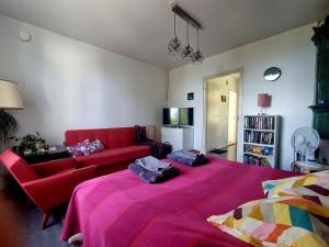 a bedroom with a large bed and a red couch at Pispalan Helmi - Koti Näköalalla in Tampere