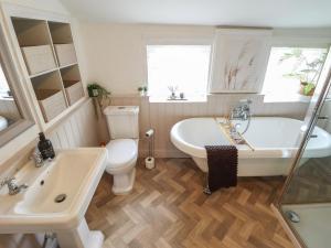 a bathroom with a tub and a toilet and a sink at Pax Cottage in Beccles +15 photos