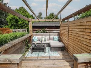 a wooden patio with a couch and a table at Pax Cottage in Beccles