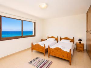 two beds in a room with a view of the ocean at Villa Serena in Pomos +24 photos