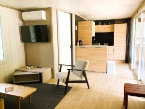 a living room with a chair and a kitchen at Chalet HABIA TXIKIA 4 pers, neuf, sur Hasparren, calme, avec piscine et climatisation, Pays Basque in Hasparren
