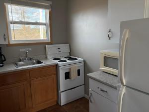 a kitchen with a stove and a sink and a refrigerator at The Sunshine Inn in Parrsboro