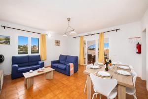 a living room with blue couches and a table at Villa Mares in Cala en Porter